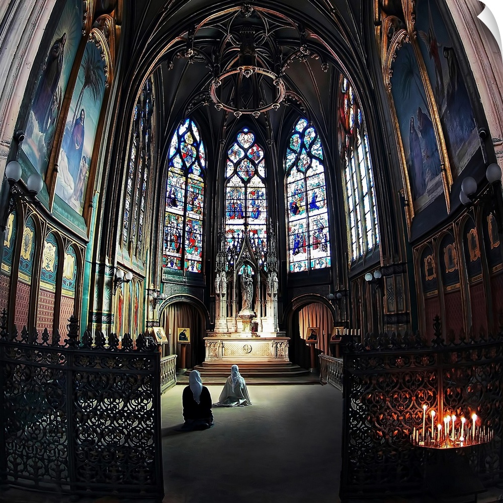 Two women kneel before an altar in front of intricate stained glass windows in a church in Paris.
