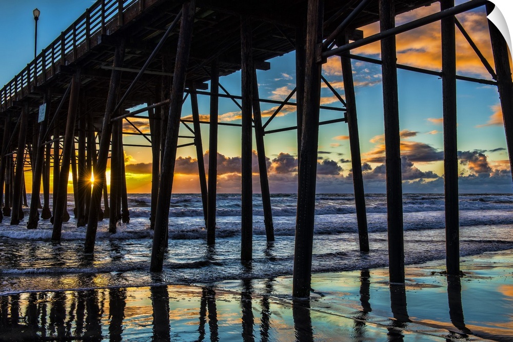 The sun peaks through the pilons of the Oceanside Pier. Oceanside is 35 miles North of San Diego, California, USA