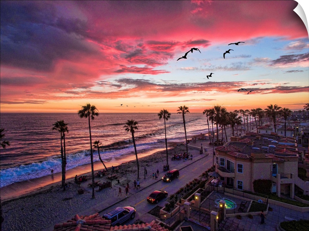 Colorful sunset with seabirds passing over the coastline in Oceanside, California, USA.