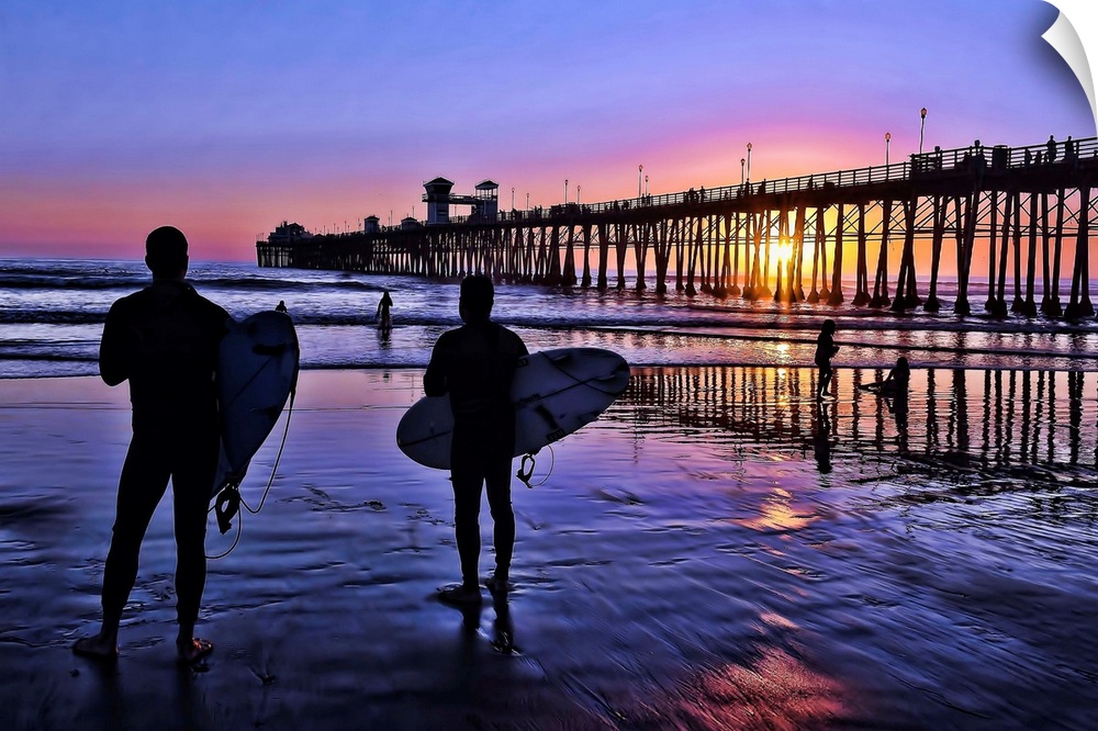 Surfers at sunset near the iconic Oceanside Pier. Oceanside is 35 miles North of San Diego, California, USA.