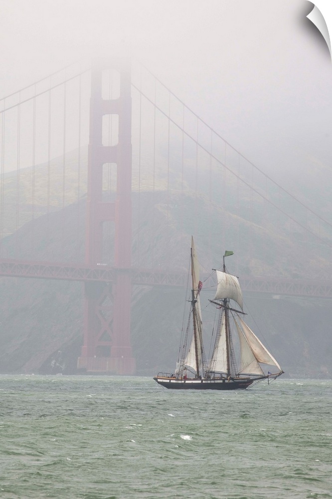 A two masted schooner sails under the Golden Gate Bridge.