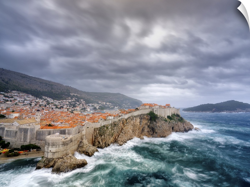 A view towards Dubrovnik Old Town with stormy seas below the city walls.