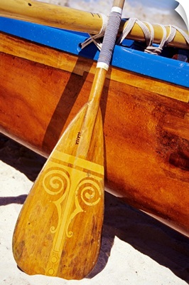 Close-Up Detail Of Wooden Paddle And Outrigger Canoe On Beach