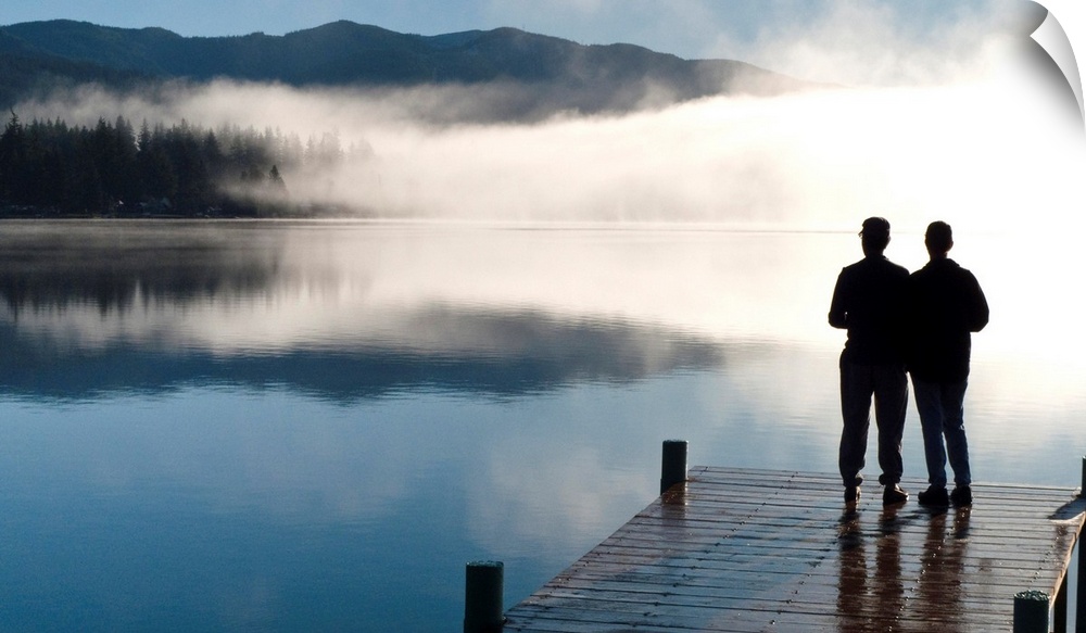 Couple standing on a dock and silhoutted against the fog lifting from Lake Whatcom during Winter, Bellingham Washington, USA