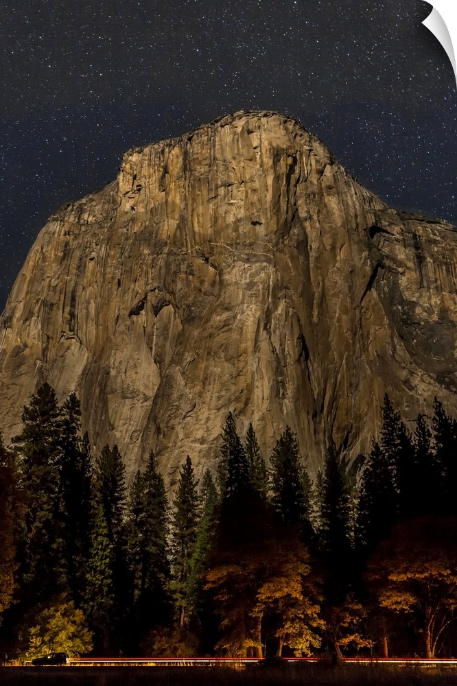 A vehicle drives along Northside Drive in front of El Capitan at night in Yosemite Valley, Yosemite National Park. Califor...