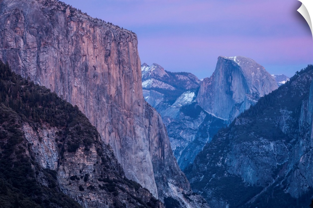 Shades of pink and lavender are reflected on El Capitan, Half Dome and winter clouds at dusk in Yosemite National Park, as...