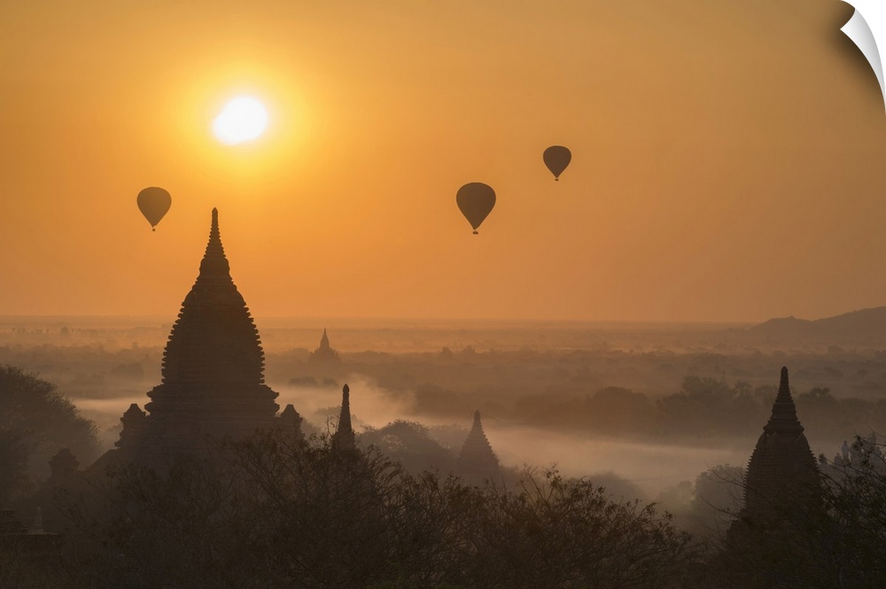 Hot air balloons flying over temples on a misty morning at Bagan.