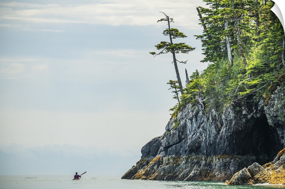 Kayaker paddling through the calm waters in the beautiful scenery of Prince William Sound; Alaska, United States of America