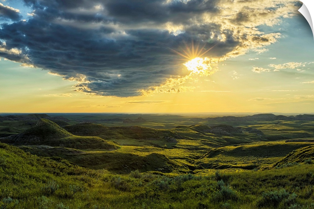 The sun shines through a cloud over the Killdeer Badlands, Grasslands National Park, Saskatchewan, Canada.