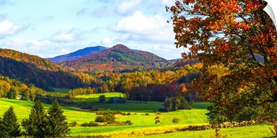 Landscape of forests on the hills with autumn colored foliage and lush green fields