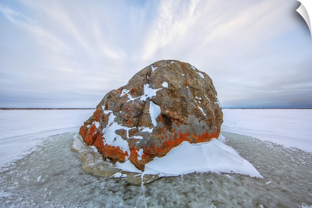 Large lichen covered rock in a frozen lake situated on the flats beside hudson's bay, Manitoba, Canada