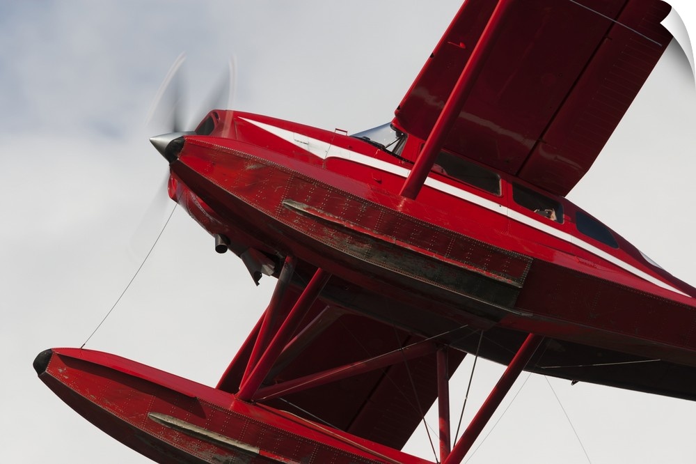 Low Angle View Of A Red Float Plane Against A Cloudy Sky; Alaska, United States Of America