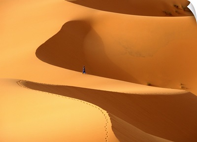 Morocco, Berber 'blue man' walking through sand dunes in Erg Chebbi area, Sahara Desert