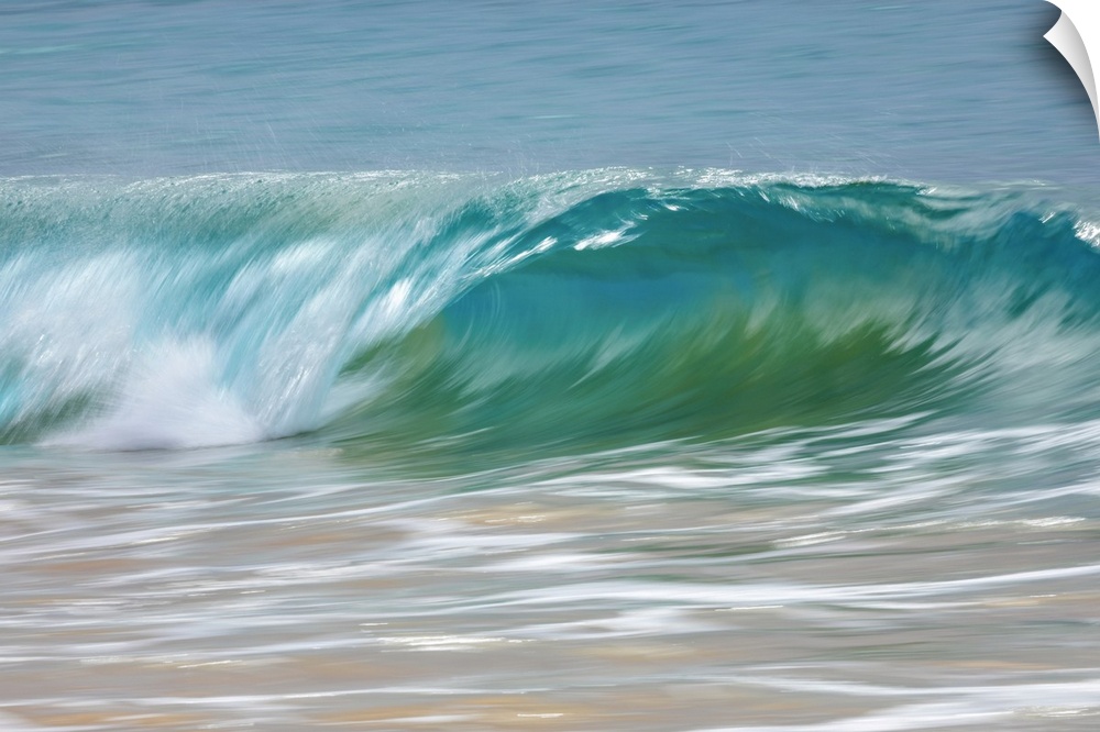 Motion blur of blue rolling waves rolling into the golden sand at the shore; Kihei, Maui, Hawaii, United States of America.