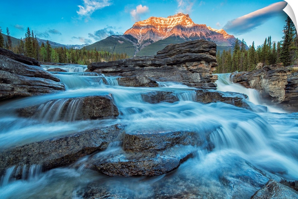 Sunset lights up Mount Fryatt as the Athabasca River flows over Athabasca Falls in Jasper National Park, Alberta, Canada.