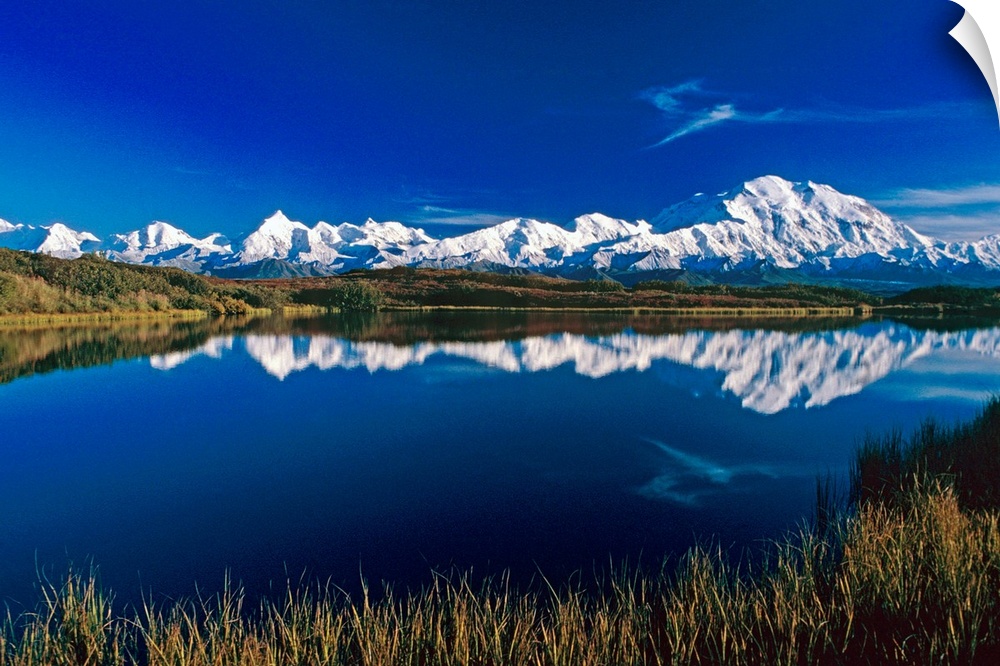 Photograph of snow covered mountain range with waterfront.  The sky is clear and the mountains are reflected in the water.