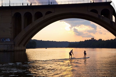 Paddleboarders glide on the Potomac River under the Key Bridge in Georgetown; Georgetown, District of Columbia, United States of America