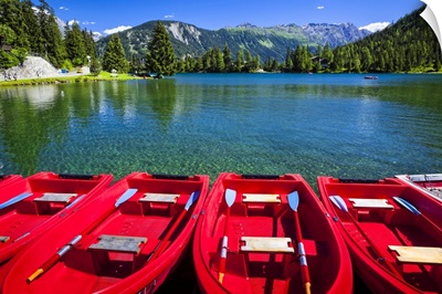 Red boats lined up at Champex Lake with a mountain range in the background