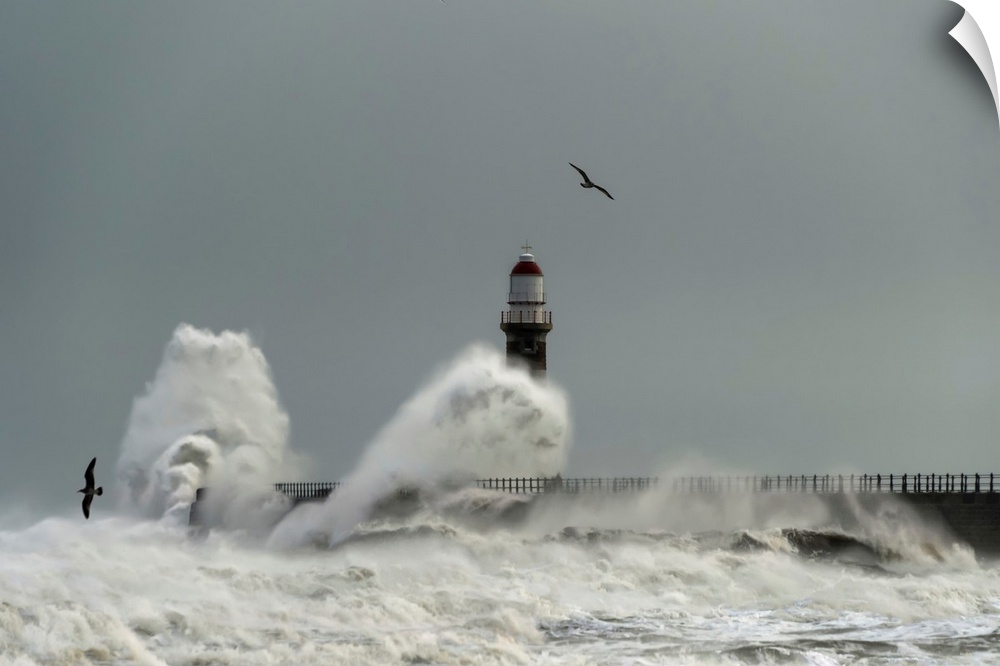 Roker lighthouse and waves from the river ware crashing onto the pier. Sunderland, Tyne and Wear, England.