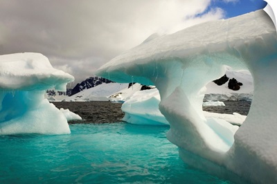 Sculpted icebergs under clouds near the shore of Couverviller Island.
