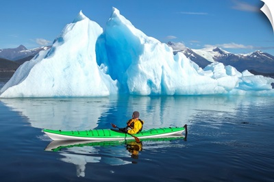 Sea Kayaker Paddles Beside An Iceberg, Alaska