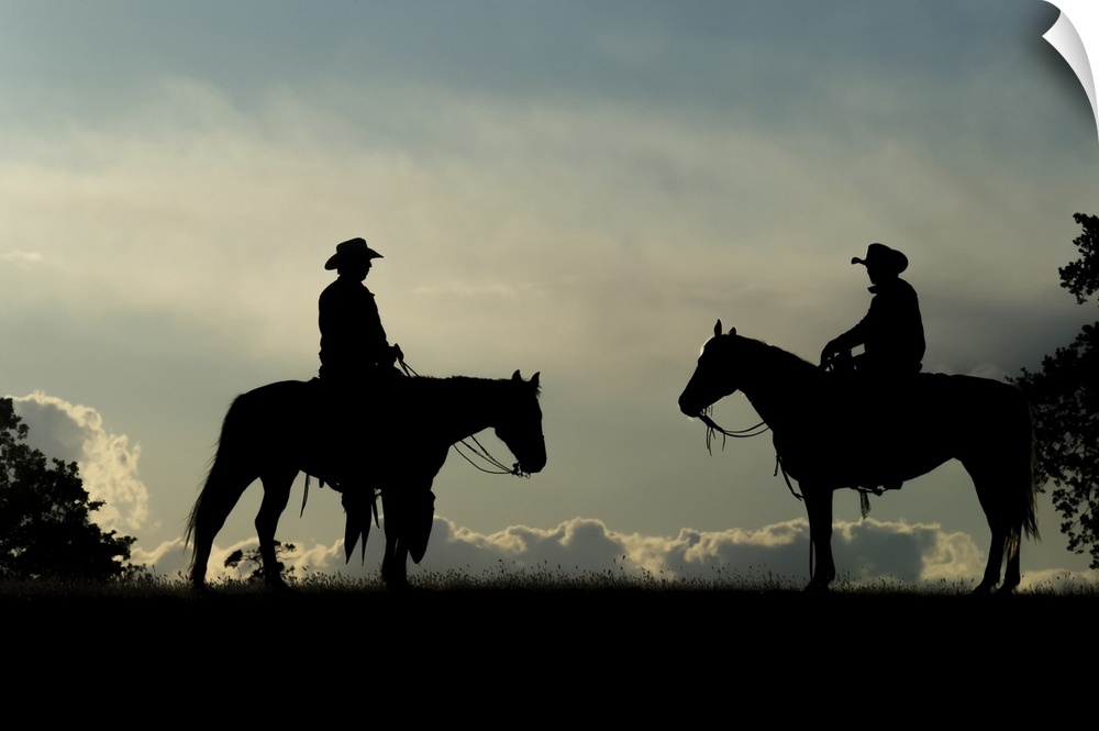 Silhouette of two cowboys on horses against a cloudy sky; Montana, United States of America.