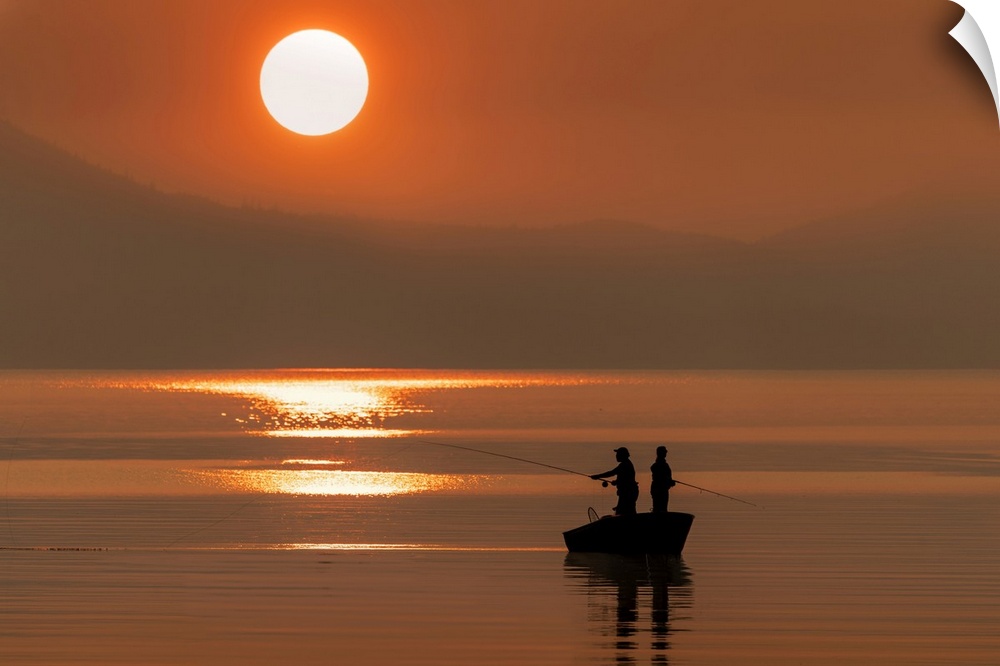 Silhouetted anglers standing in a boat fishing for salmon at sunset; Juneau, Alaska, United States of America