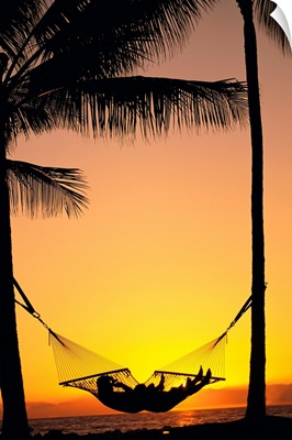 Silhouetted Couple Laying In Hammock On Beach At Sunset