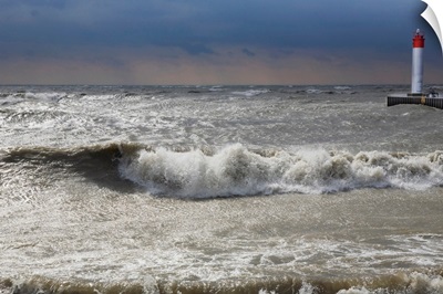 Storm waves crashing on a beach near a lighthouse on Lake Ontario, Whitby, Ontario