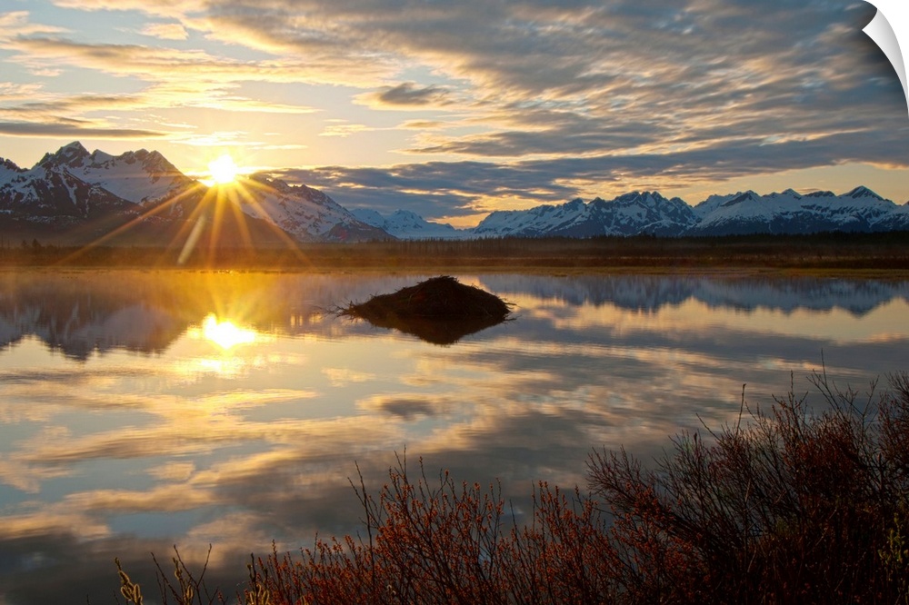 Sun rises over the Chugach Mountains at a pond with a beaver lodge along the Copper River Highway in the Chugach National ...