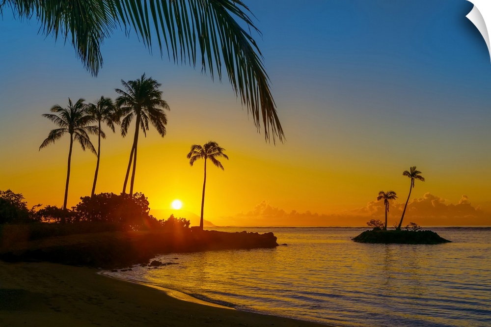 Sunrise at Kahala Beach, Waialae Beach Park, with a glowing yellow sun and warm coloured lights reflected in the tranquil ...