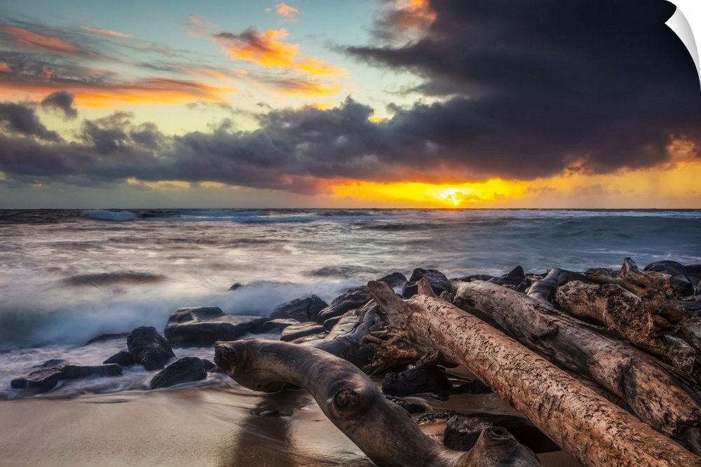 Sunrise over beach and ocean with a storm cloud and rain in the distance; Kauai, Hawaii, United States of America