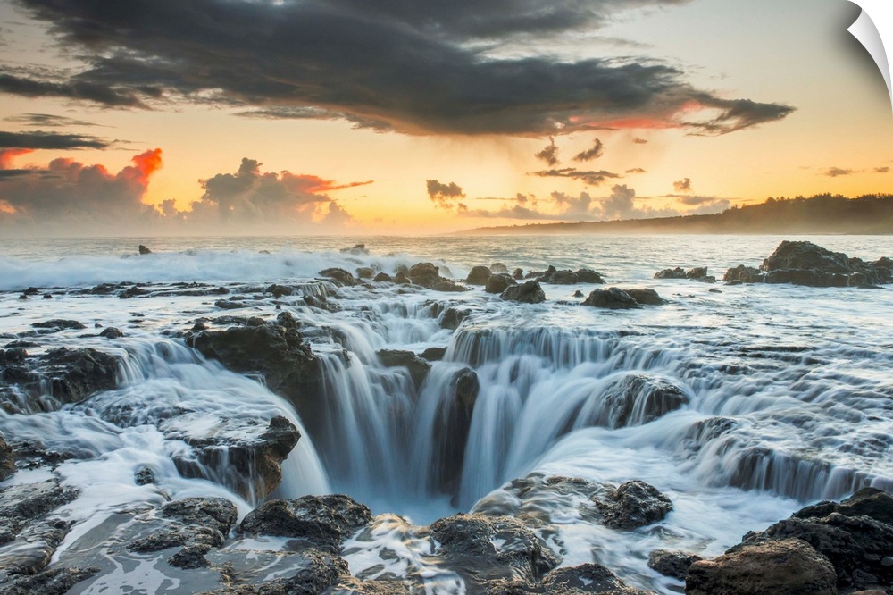 Surf spills into a hole in a rock outcrop on the east side of Kauai. Kauai, Hawaii, United States of America.