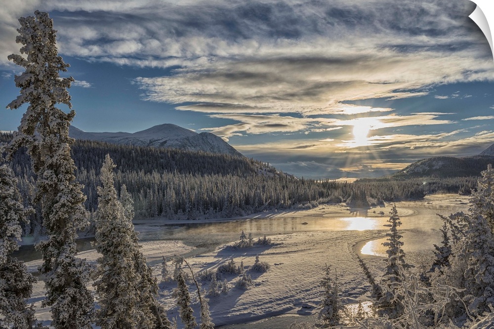 The sun breaks through the clouds above the Takhini River on a late winter afternoon, near Whitehorse. Yukon, Canada.