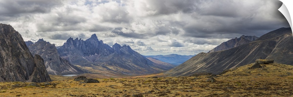 Men standing on a boulder in the distance in Tombstone Territorial Park in autumn. Yukon, Canada.