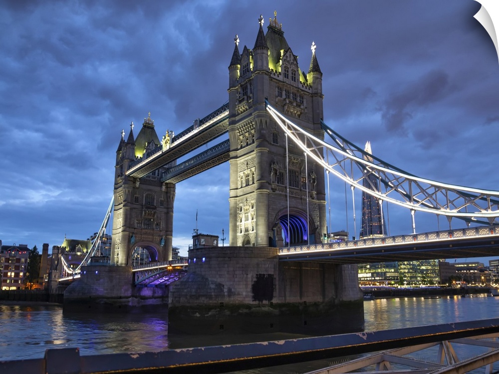Tower Bridge illuminated at dusk and reflected in the tranquil water of the River Thames; London, England.