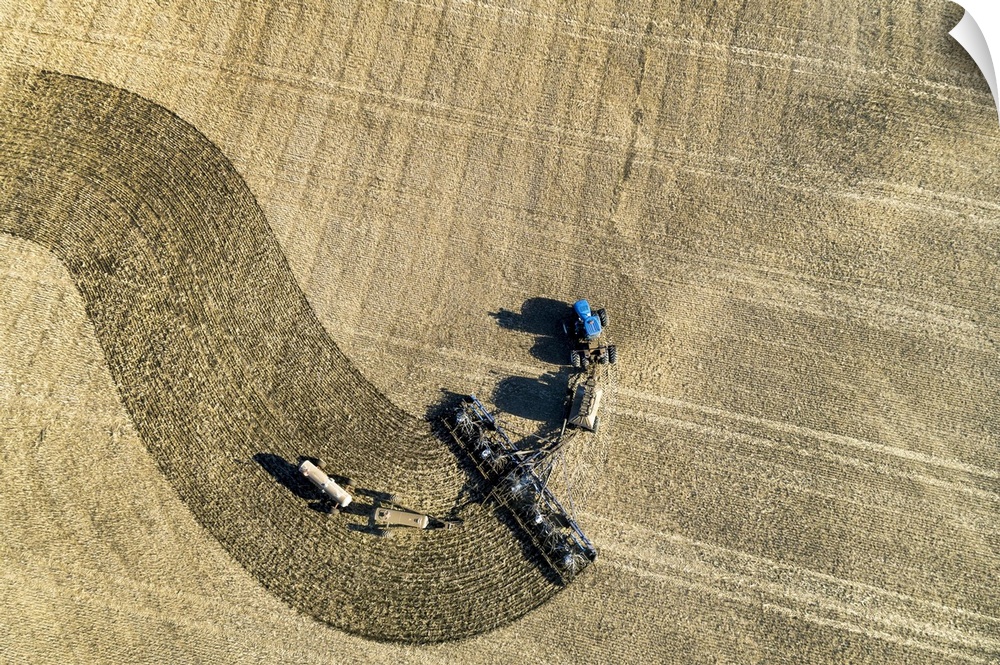 Aerial view of a tractor pulling an air seeder, seeding a field; Beiseker, Alberta, Canada
