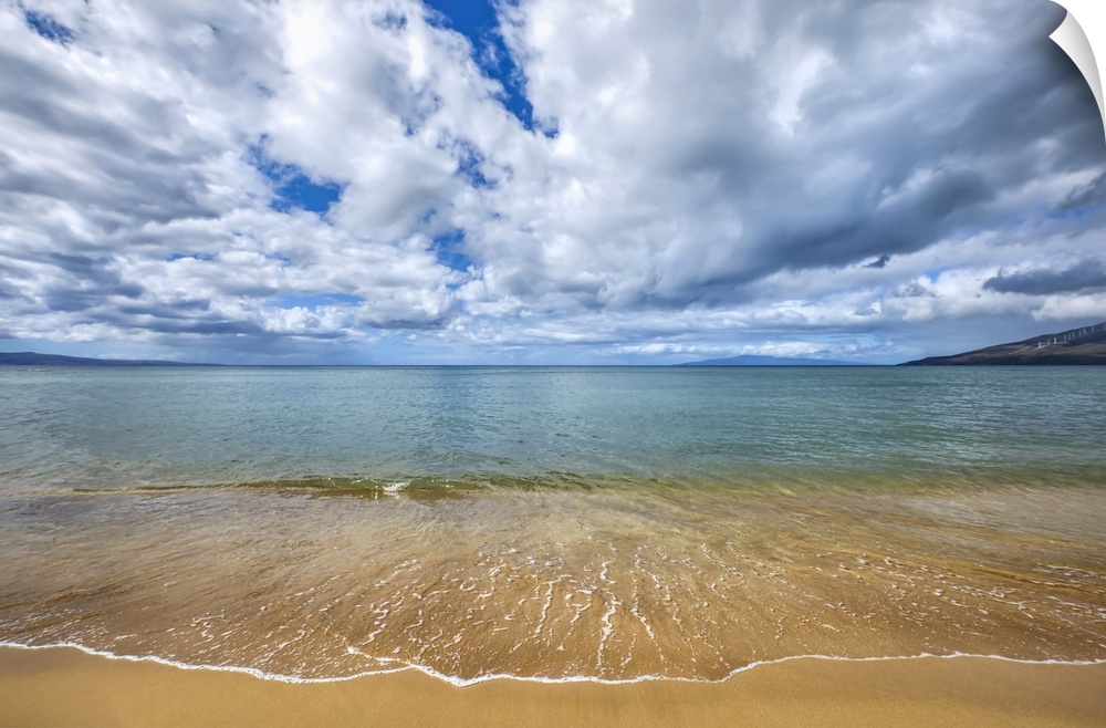 Tranquil surf washes up on golden sand and a view of the coastline of the island of Maui; Kihei, Maui, Hawaii, United Stat...