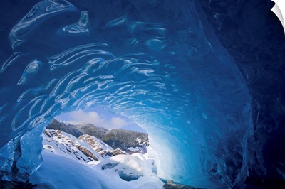 View from inside an ice cave looking outward at the snowcovered landscape