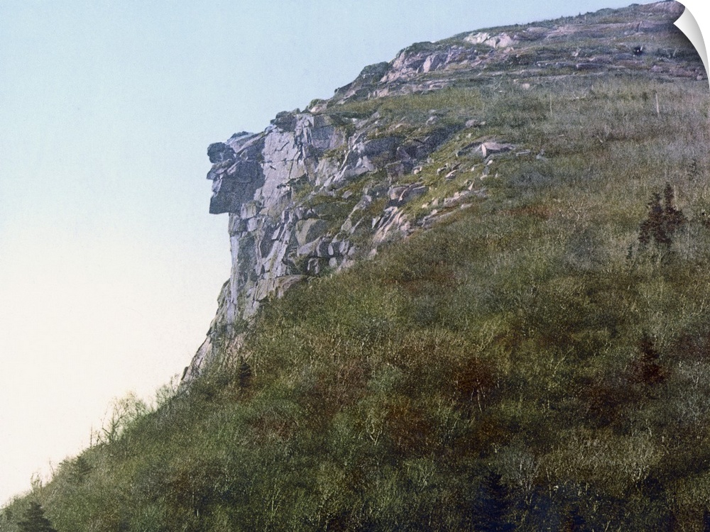 Photo on canvas of the face of a man made out of rocks hanging on a cliff of a mountain.
