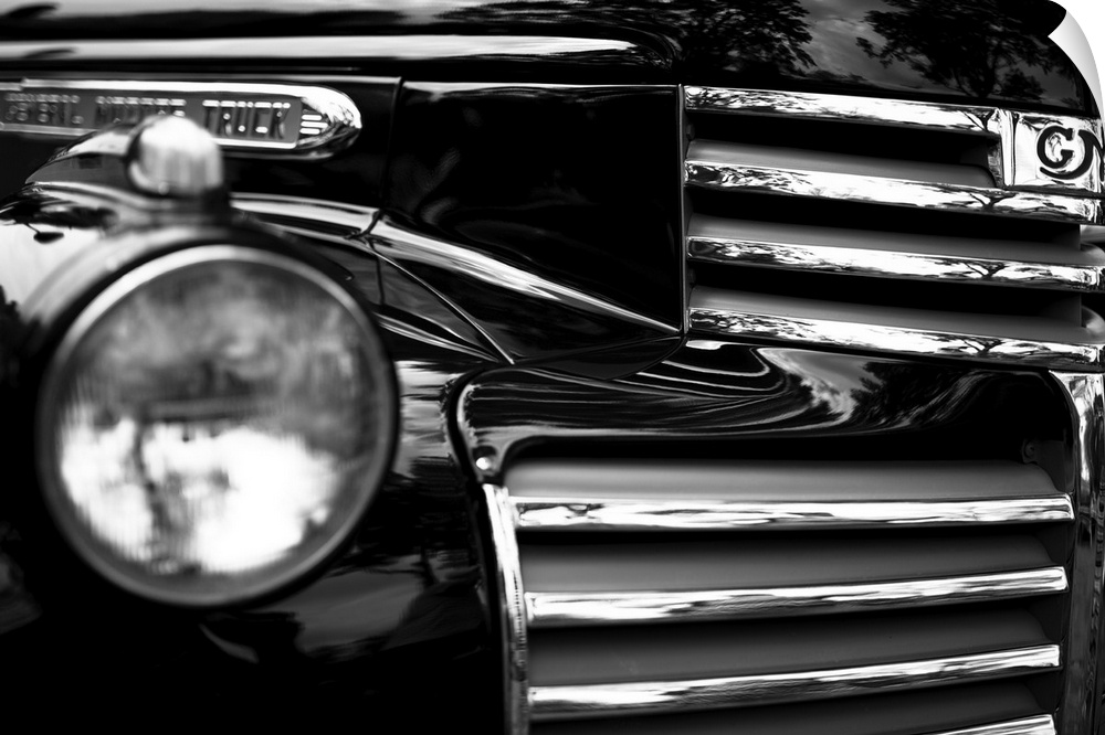 Black and white photo of the headlight and grille of a classic car.