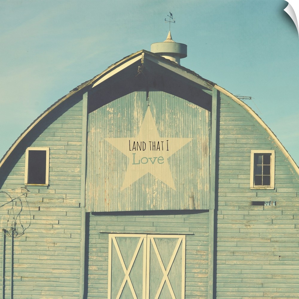 Square photograph of a blue tinted barn with a star sign that reads "Land That I Love" on the top.