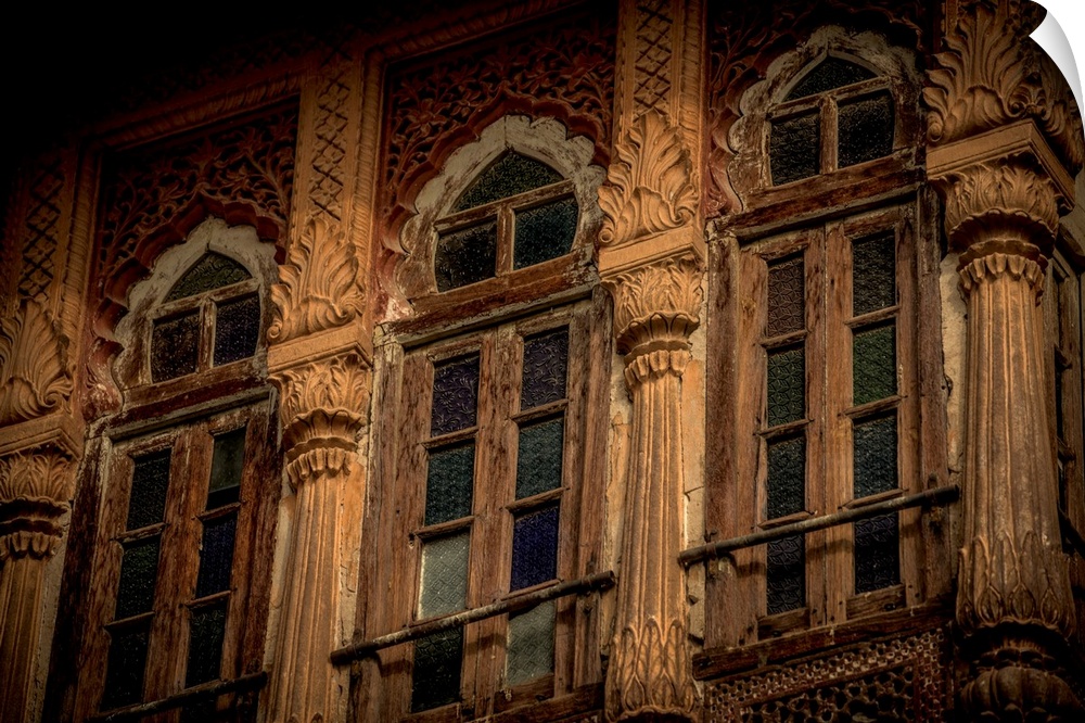 Photograph of stained glass windows with intricately detailed pillars in-between each.