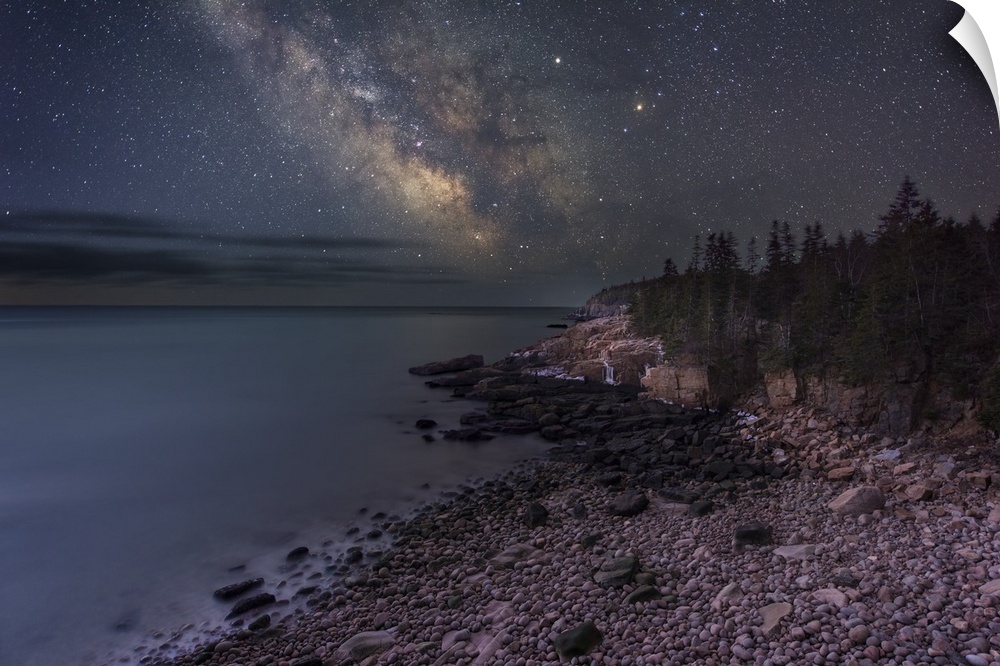 A photograph of a rocky beach under a starry night sky.