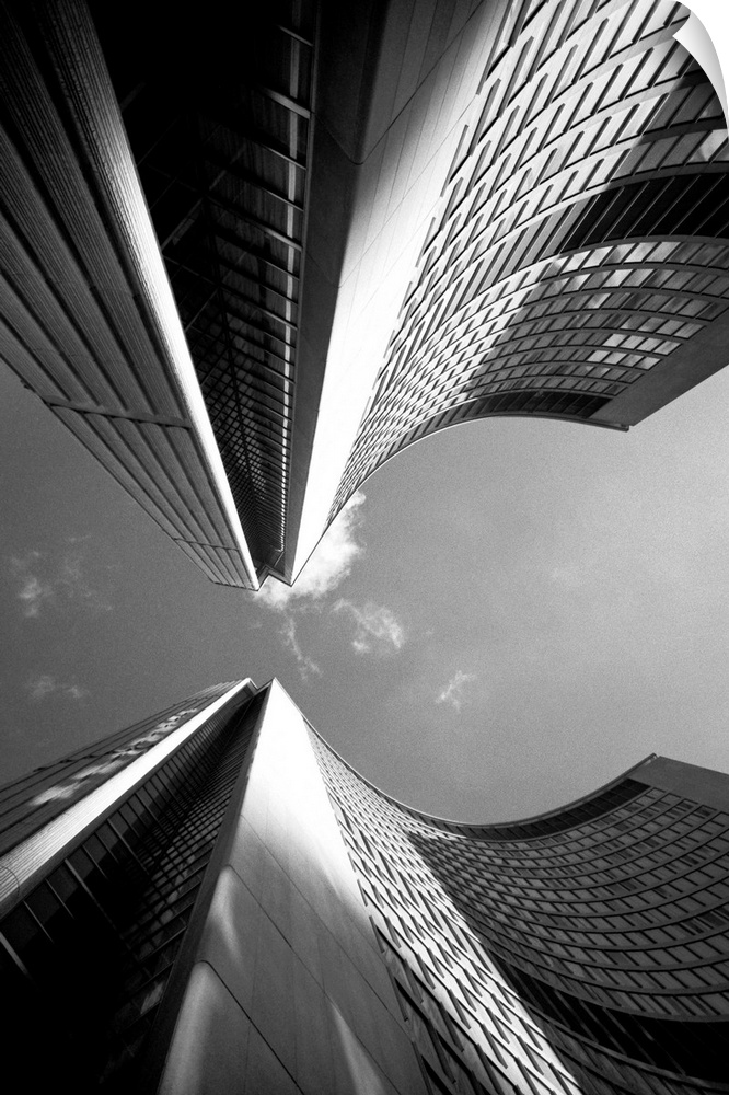Black and white photograph of a view looking straight up between two skyscrapers in a city.