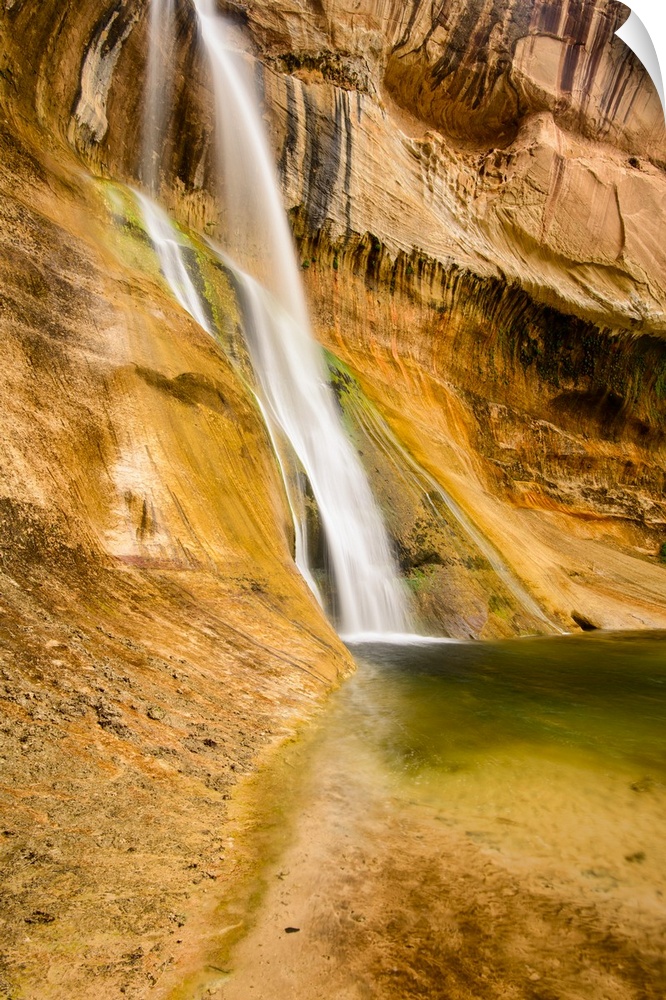 A photograph of a small waterfall streaming down a desert rock wall in an oasis.