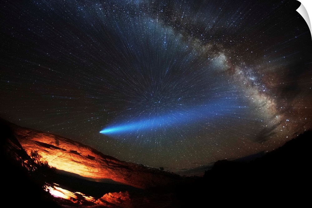 A comet and the Milky Way visible in the night sky over Arches National Park.