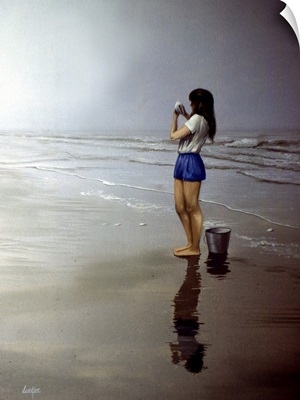 Girl Standing On Beach With Bucket By Her Feet, Looking At A Shell