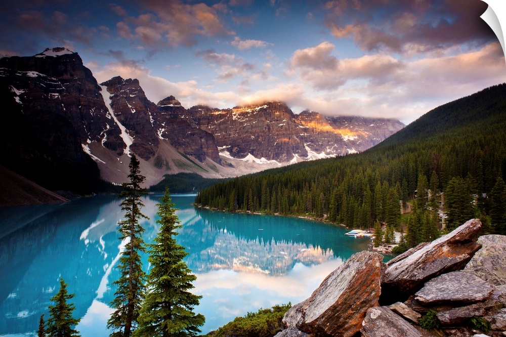 Landscape photograph of Lake Moraine surrounded bu snowy mountains and pine trees.