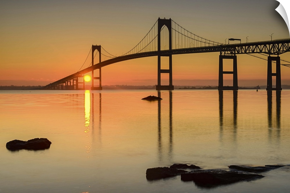 A photograph of a large suspension bridge silhouetted at sunset.
